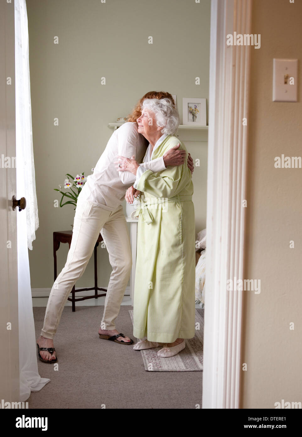 Female caregiver embracing elderly woman in bedroom Stock Photo