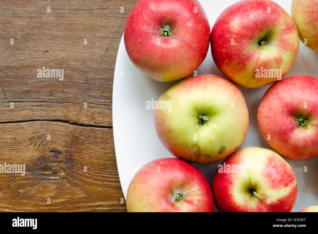 many red apple on white plate on vintage wooden table Stock Photo