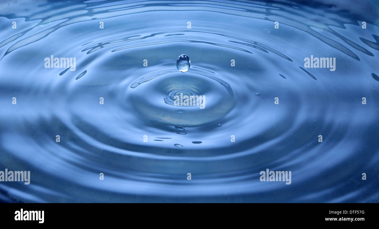 Water droplet with circular ripples and reflection Stock Photo