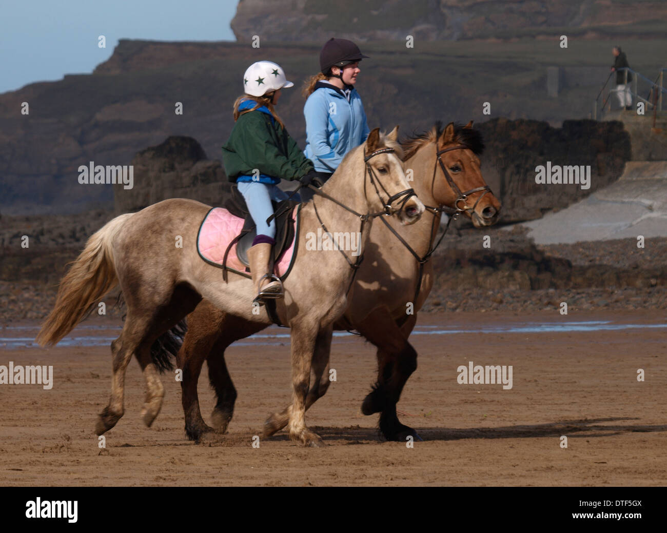 Two teenage girls horse riding on the beach, Bude, Cornwall, UK Stock