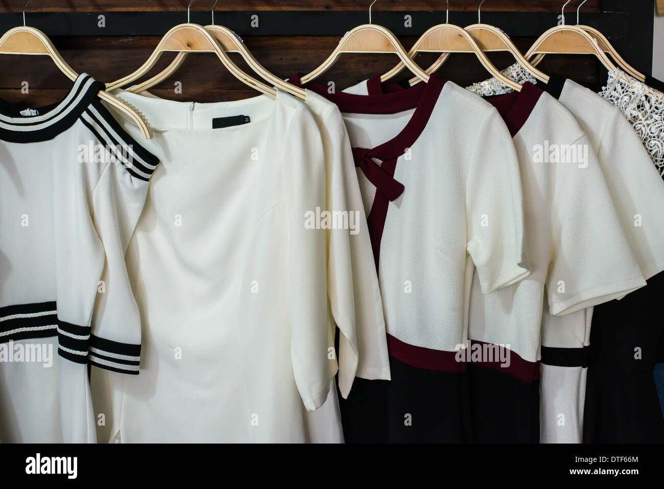 Many white blouses on hangers in the dressing room. Stock Photo