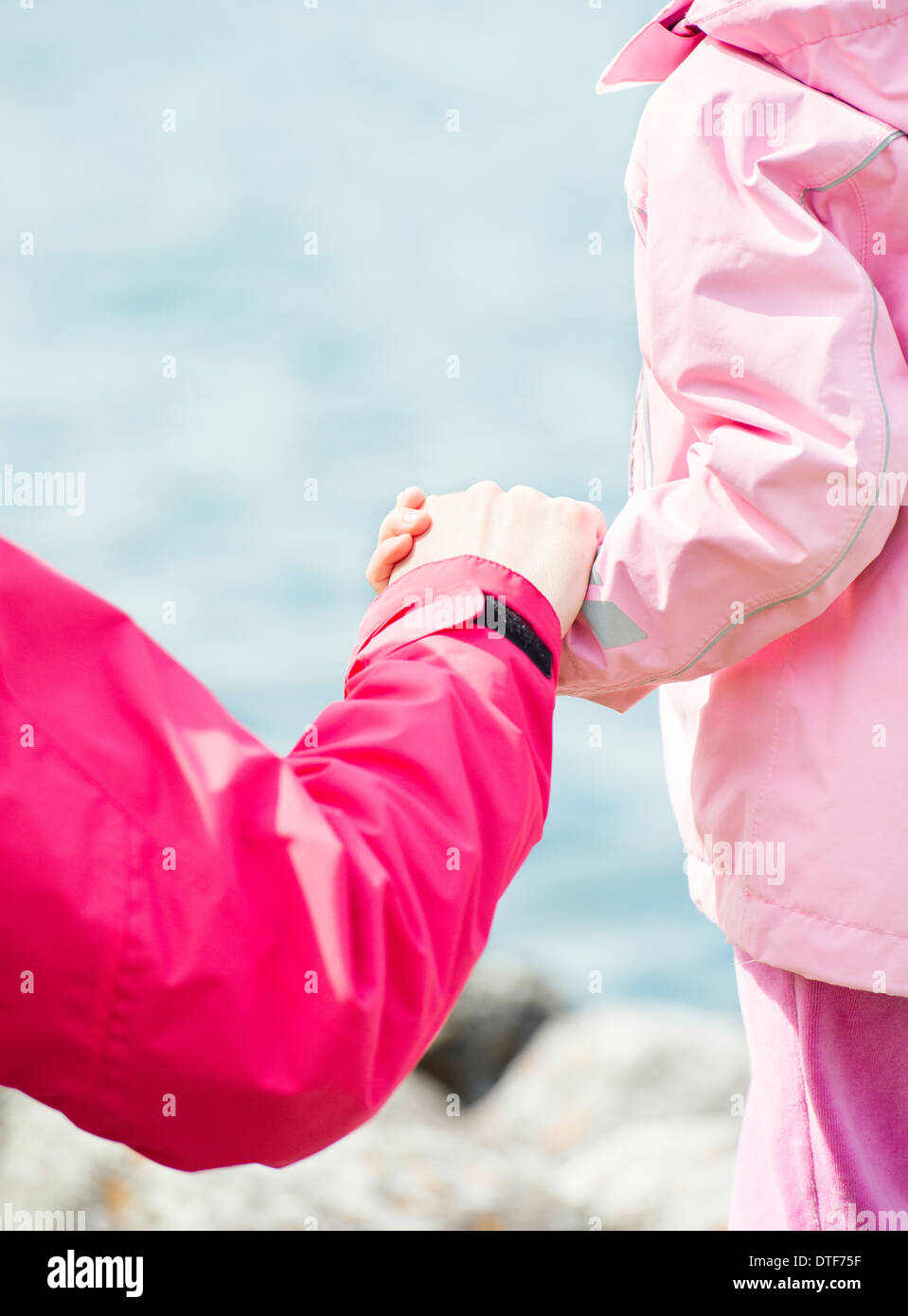 Close up of little girl and woman holding hands in nature setting Stock Photo