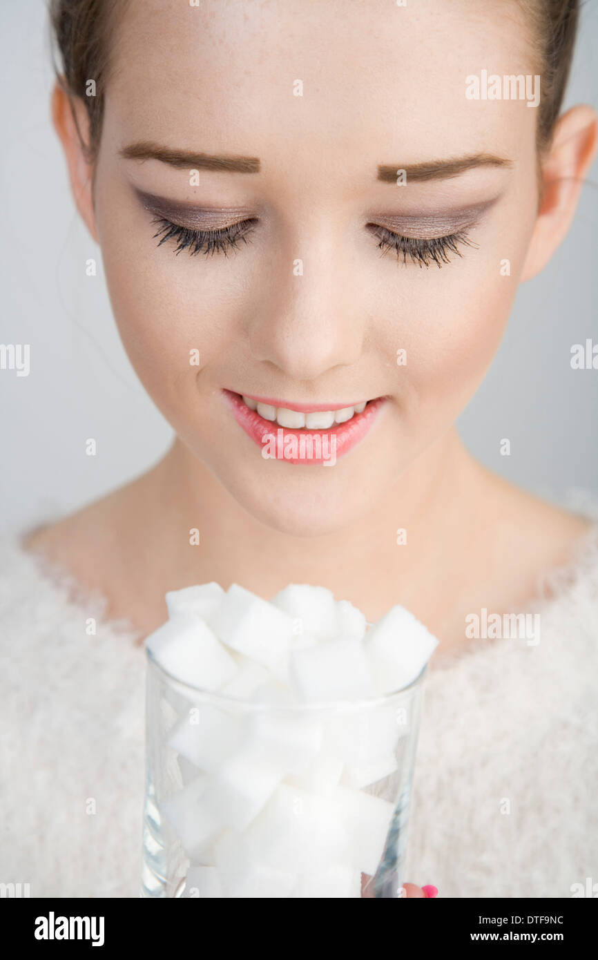 A young woman looking down into a glass full of sugar cubes. Stock Photo