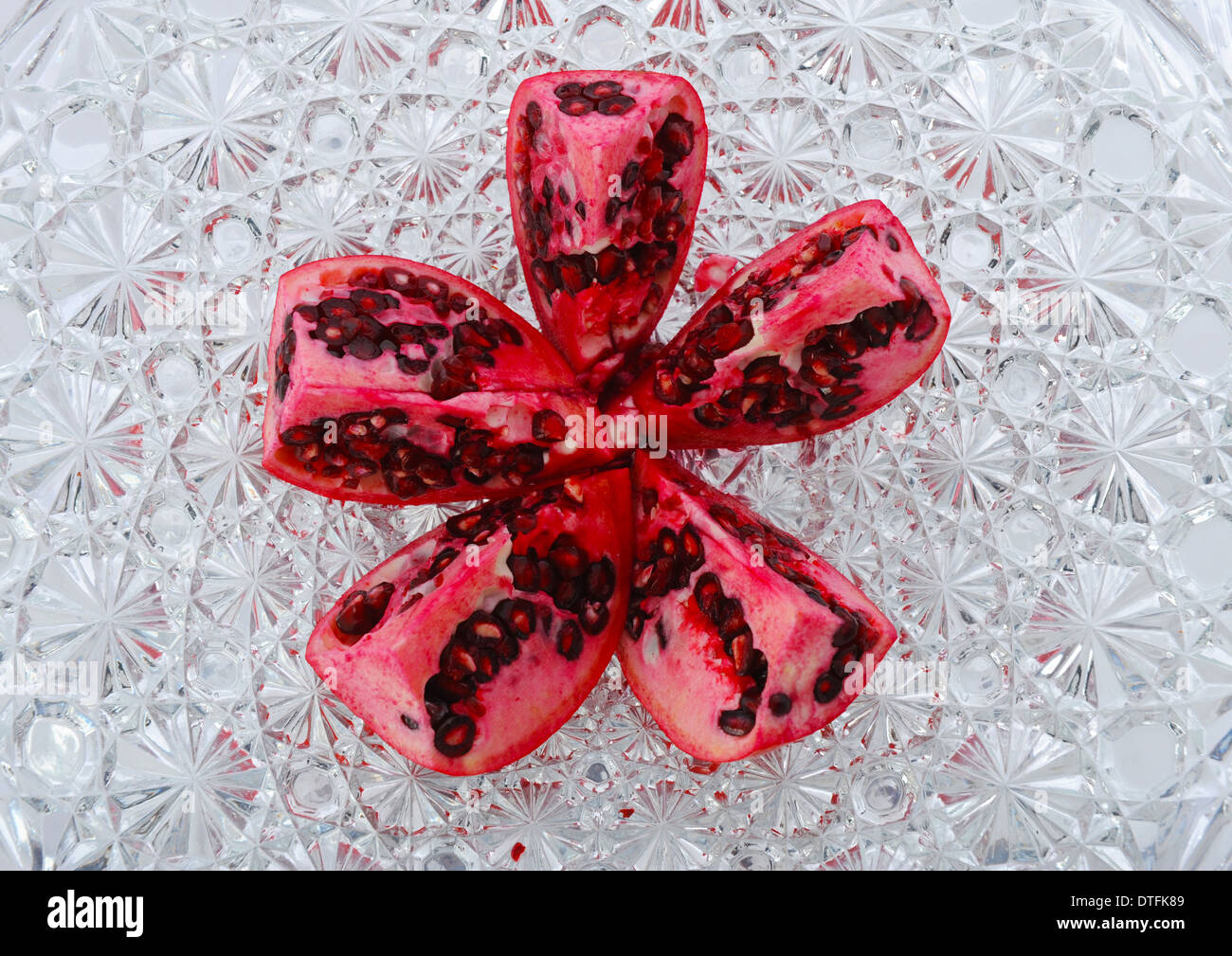 Ripe ruby red pomegranate fruit cut in columns showing rich deep red seeds covered with juicy sweet pulp. Stock Photo