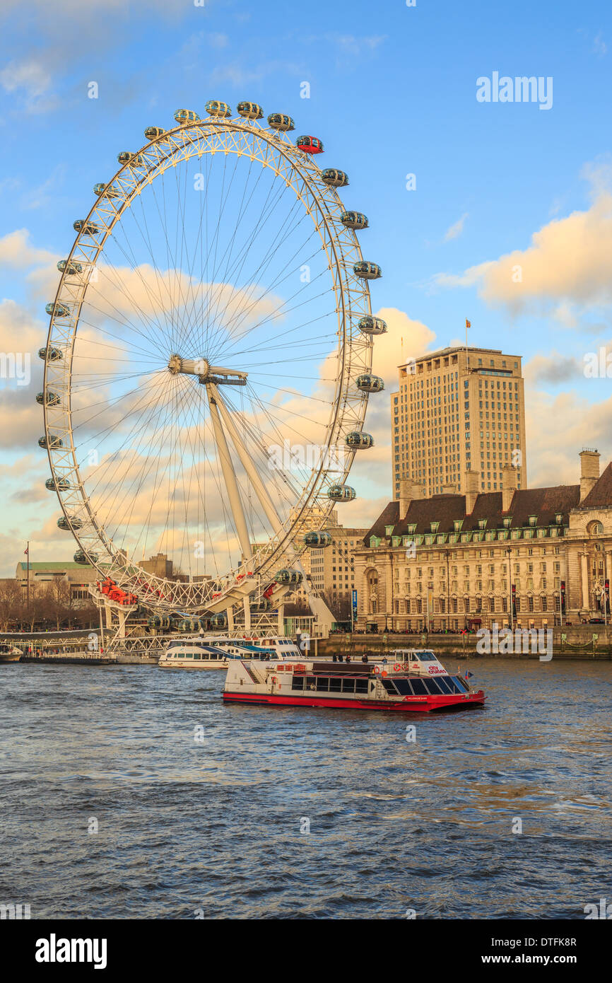 The London Eye looking from Westminster Bridge acros the Thames a with tour boat in foreground. Stock Photo