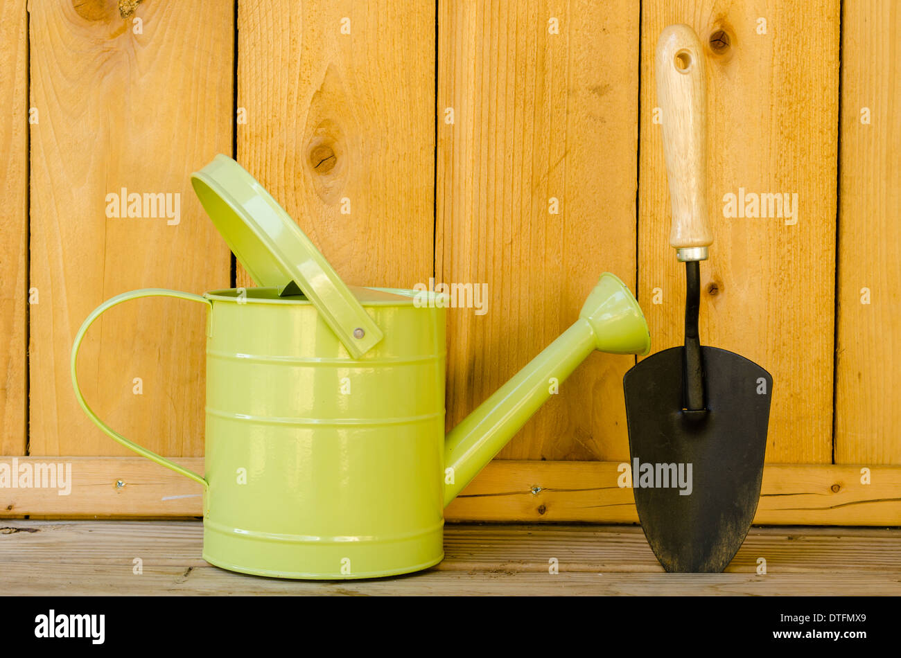 Watering can and trowel on wood background. Stock Photo