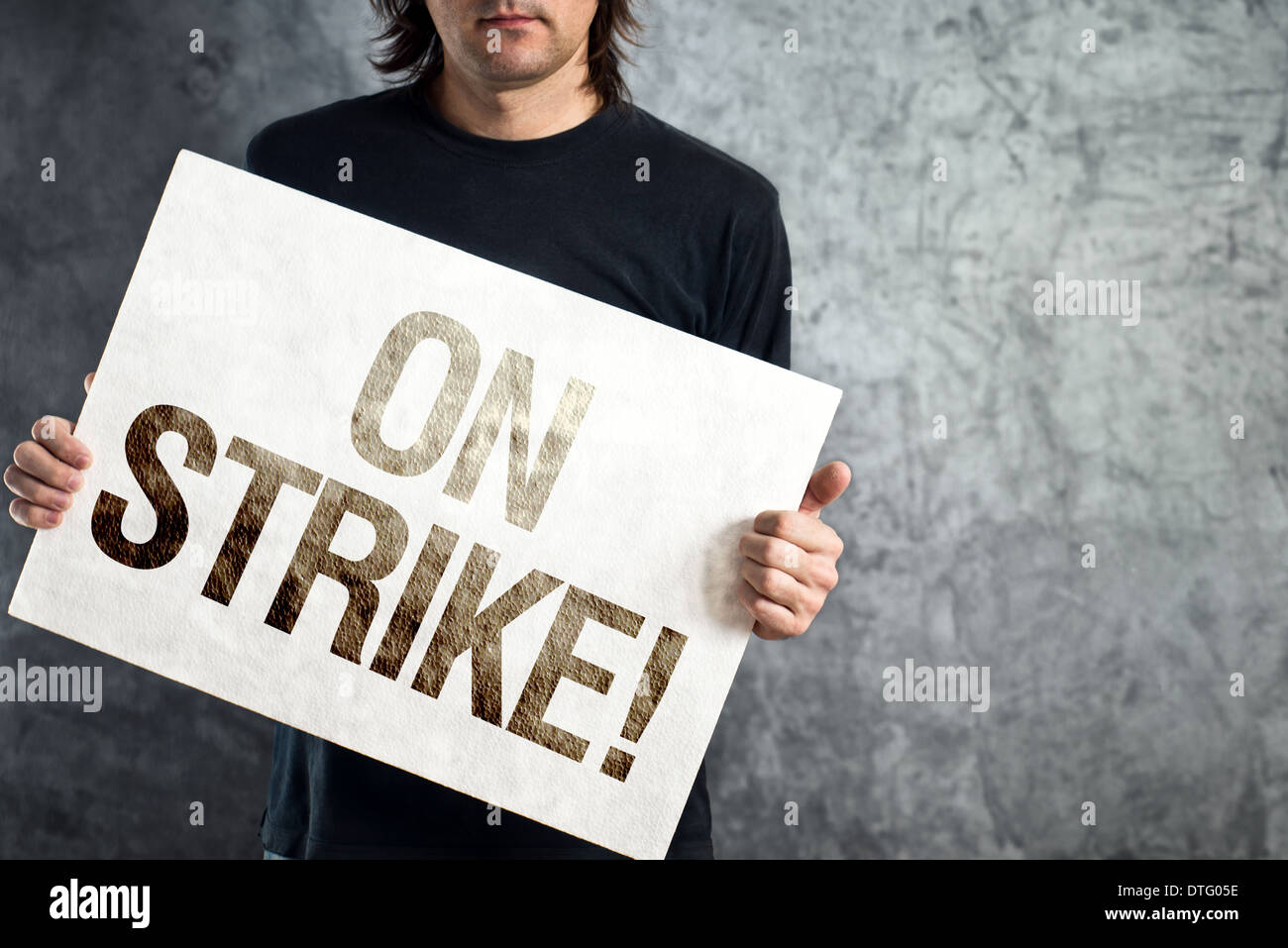Man holding banner with ON STRIKE printed protest message. Stock Photo