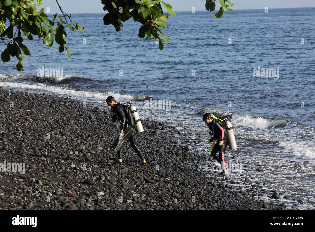 Scuba divers exit the ocean after diving in Tulamben, east Bali Stock Photo