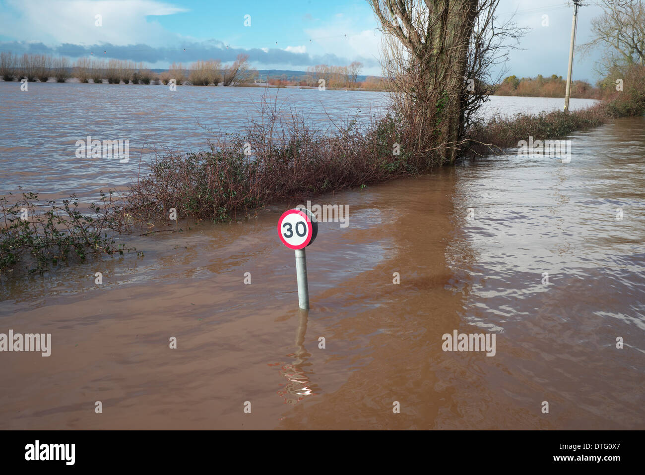Floooded road in the village of Burrowbridge on the Somerset Levels with road speed sign almost submerged Stock Photo