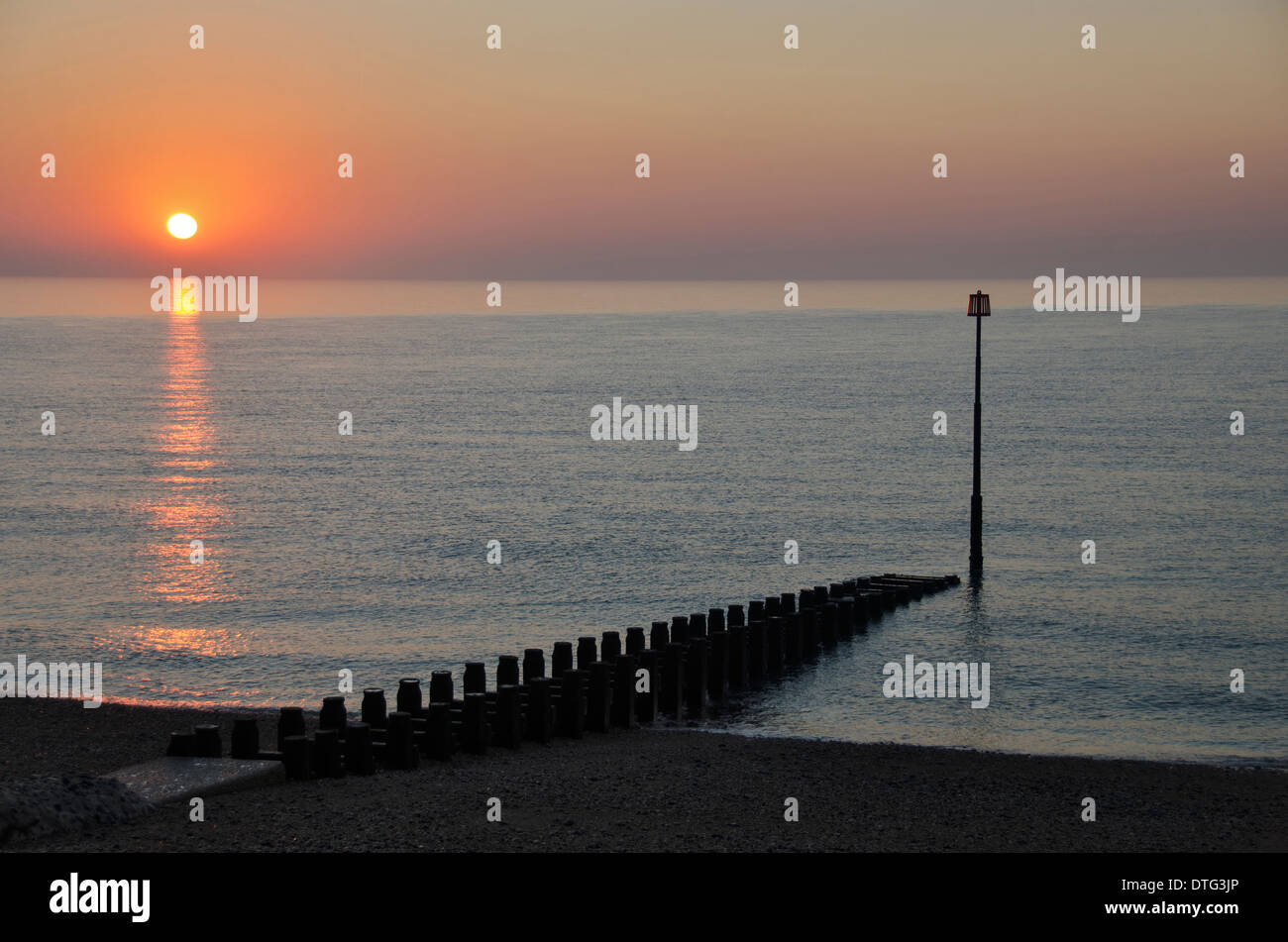 The sun rising at Eastbourne, Sussex, England, UK with a calm sea and coloured sky. Stock Photo