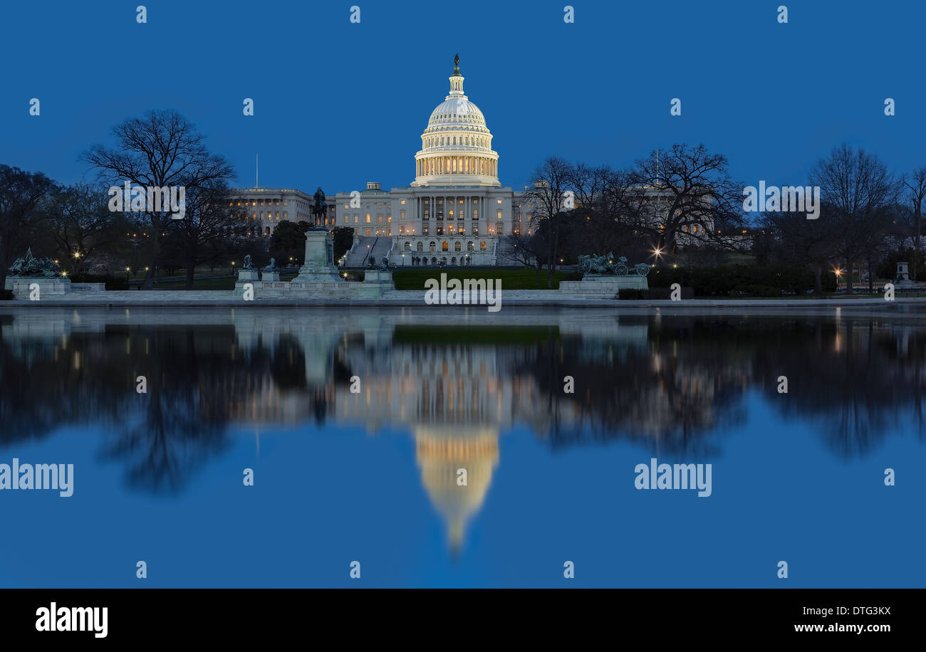 A west side view at twilight  of the regal dome and building of the United States Capitol in Washington DC. The stilled winds after sunset reflects the majestic building in the pool of water. Stock Photo