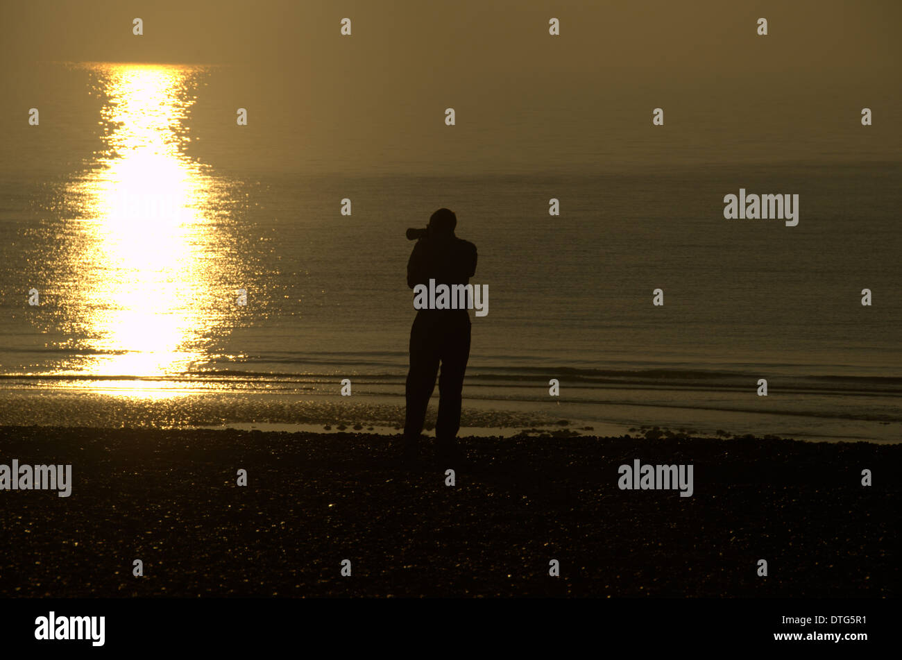 Photographer on the beach photographing the sunrise at Eastbourne in Sussex, England Stock Photo