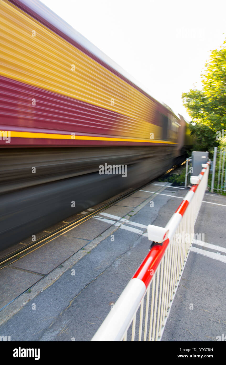 An image of a freight train taken at speed at a level crossing. Stock Photo