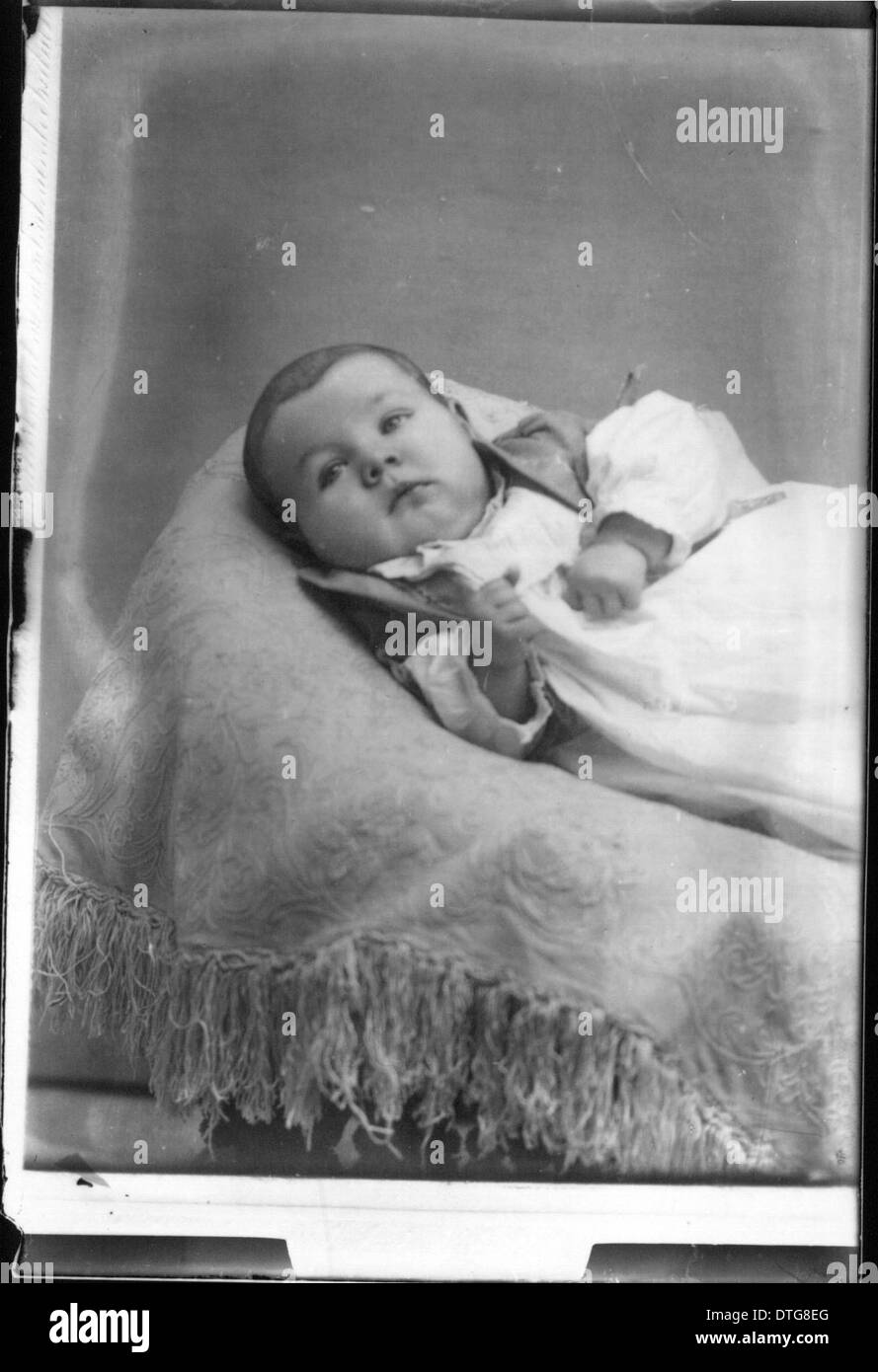 This vintage portrait photograph features an infant in a cradle ...