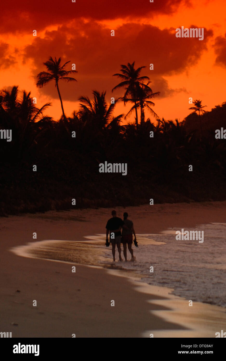 Couple walking on beach at sunset at Long Bay, Tortola, British Virgin Islands. Stock Photo