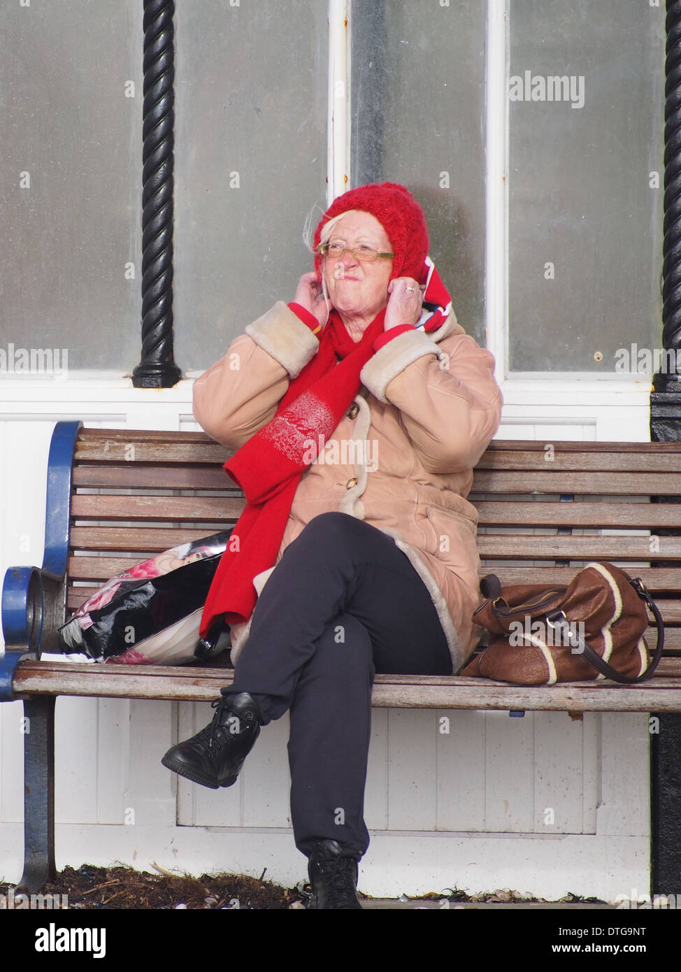 A Senior lady pulls her woolly hat over her ears to protect against the cold Stock Photo