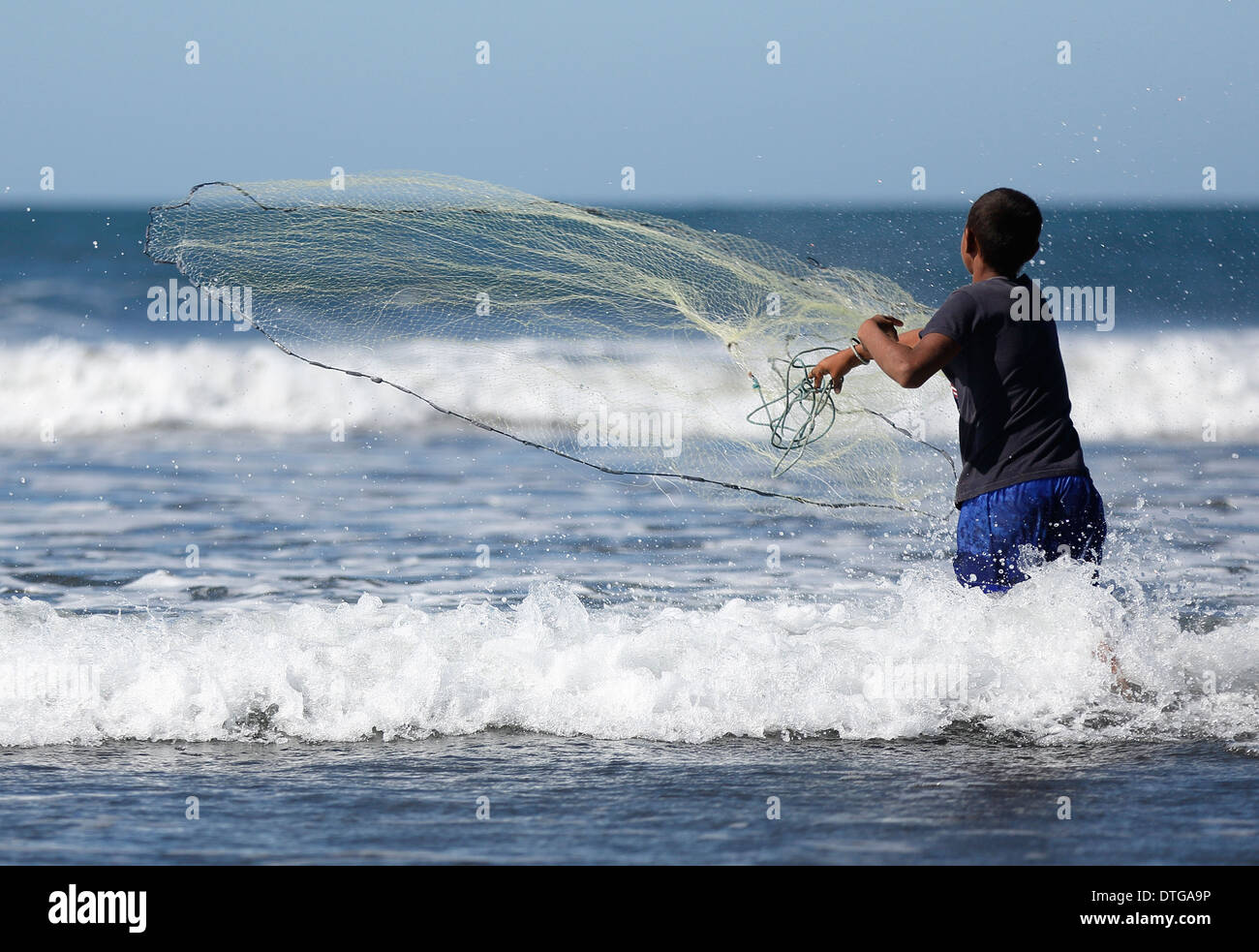 Boy casting net into the surf on the Pacific coast beach at Mechapa, Nicaragua Stock Photo