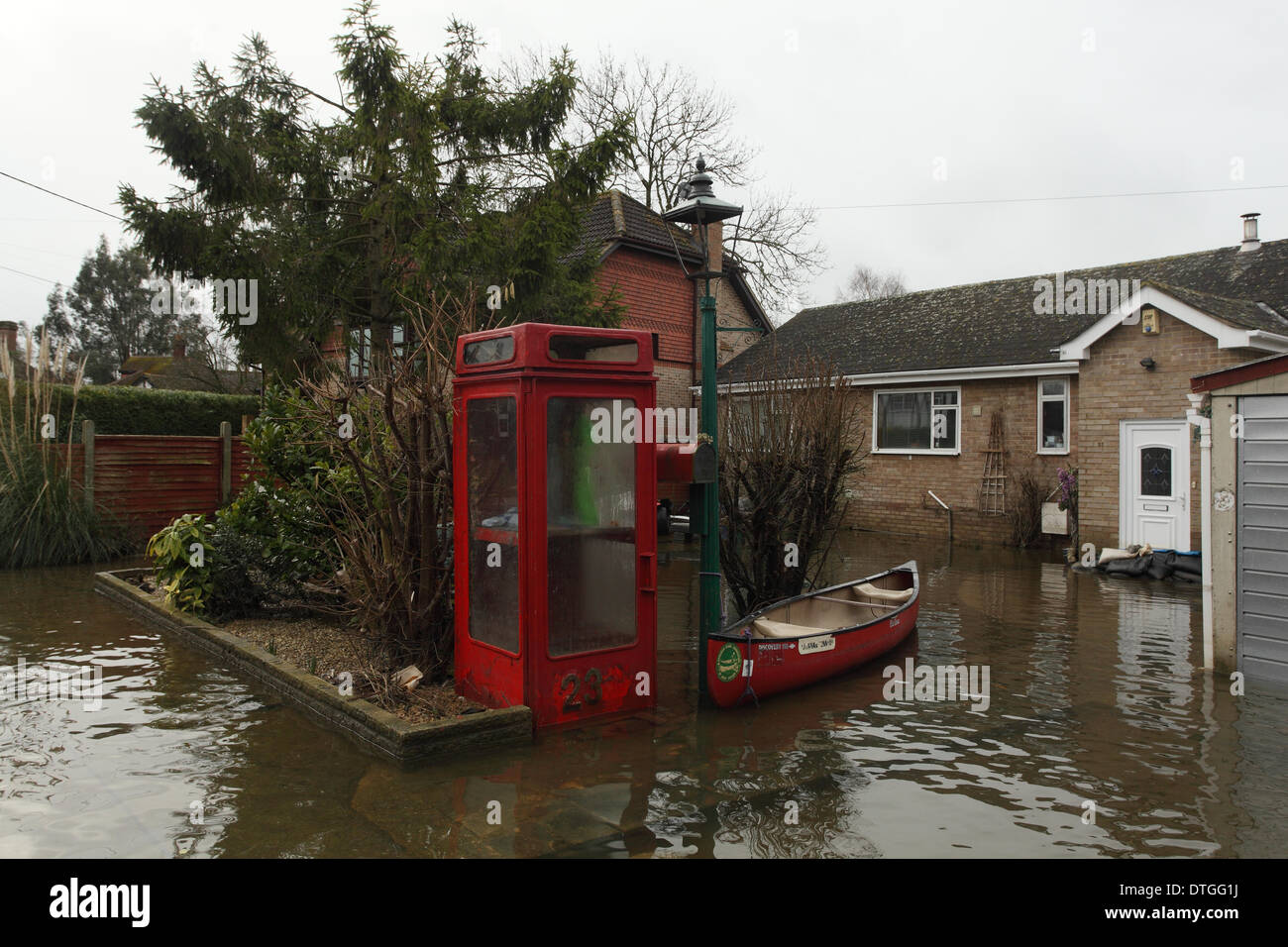 Ham Island, Thames Valley, UK. Canoe moored next to phone box  Flood waters surround homes and gardens. Stock Photo