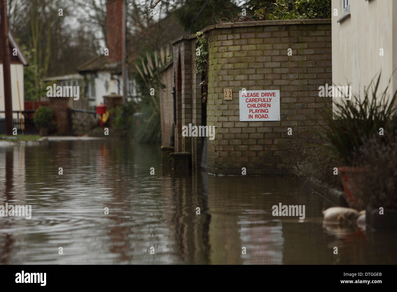 Ham Island, Thames Valley, UK. Flood waters submerge the road with a sign that reads beware children playing in the street Stock Photo