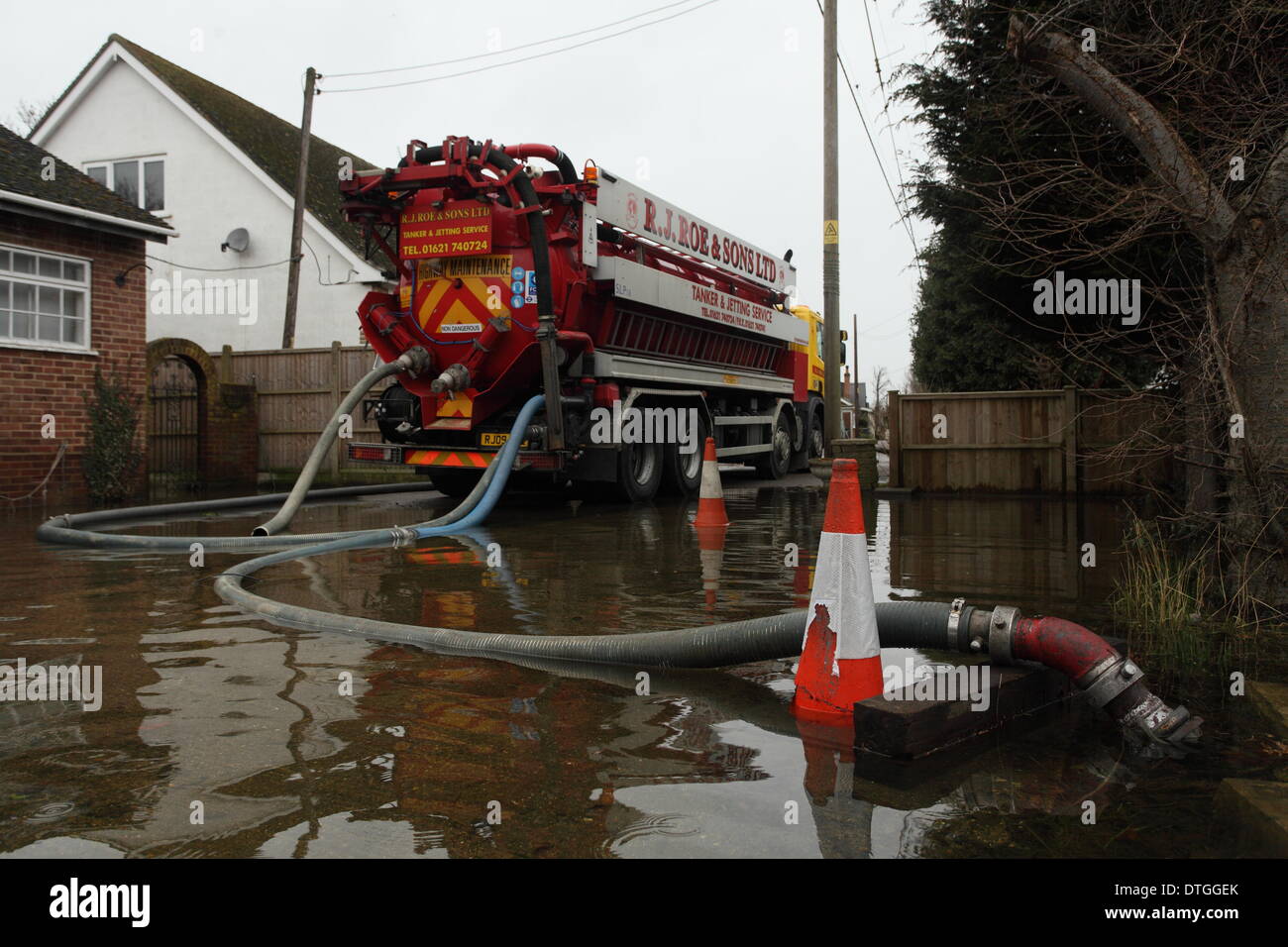 Ham Island, Thames Valley, UK. Lorry pumps water away from the flooded street. Flood waters surround homes and gardens. Stock Photo