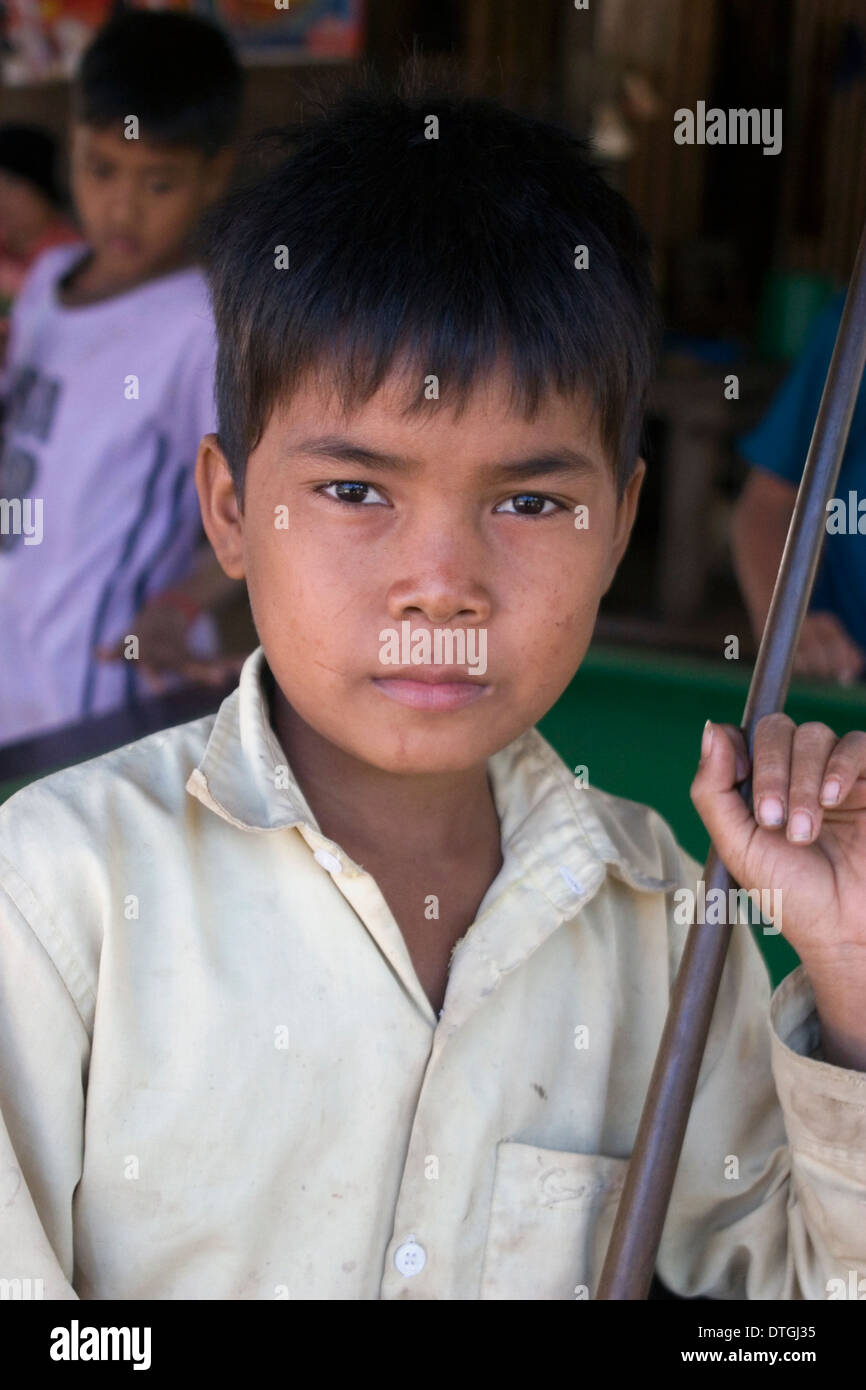 An 11 year old boy is posing for a portrait holding a pool cue stick in ...