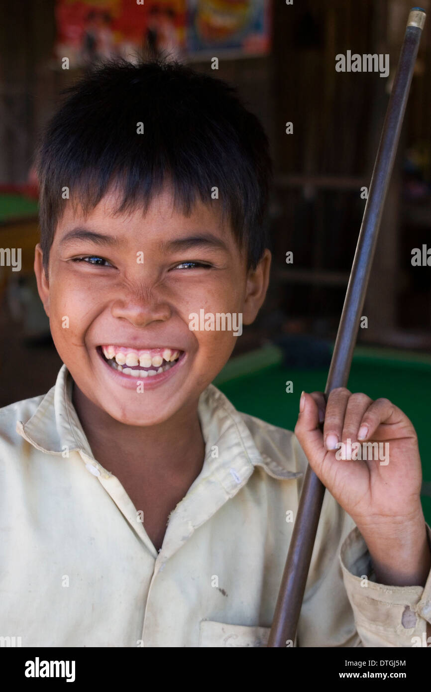 An 11 year old boy is posing for a portrait holding a pool cue stick in a pool hall in Stung Treng Cambodia. Stock Photo