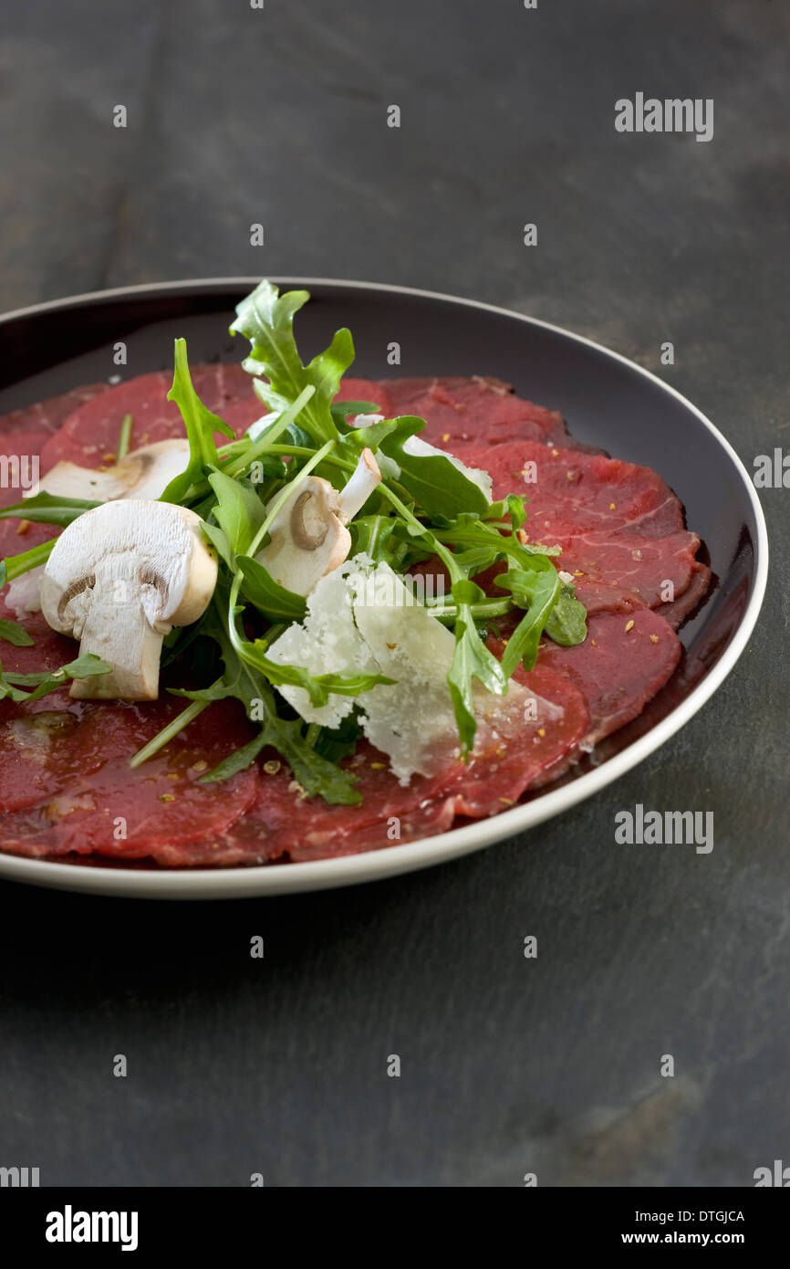Beef carpaccio with rocket lettuce,mushrooms and parmesan Stock Photo