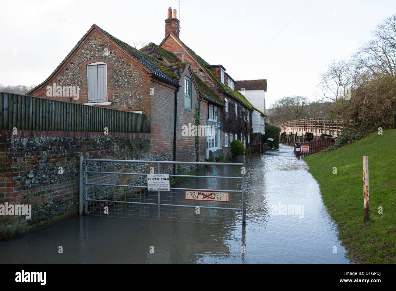 A flooded mill building next to the River Thames, river water has flood the roadway. Stock Photo