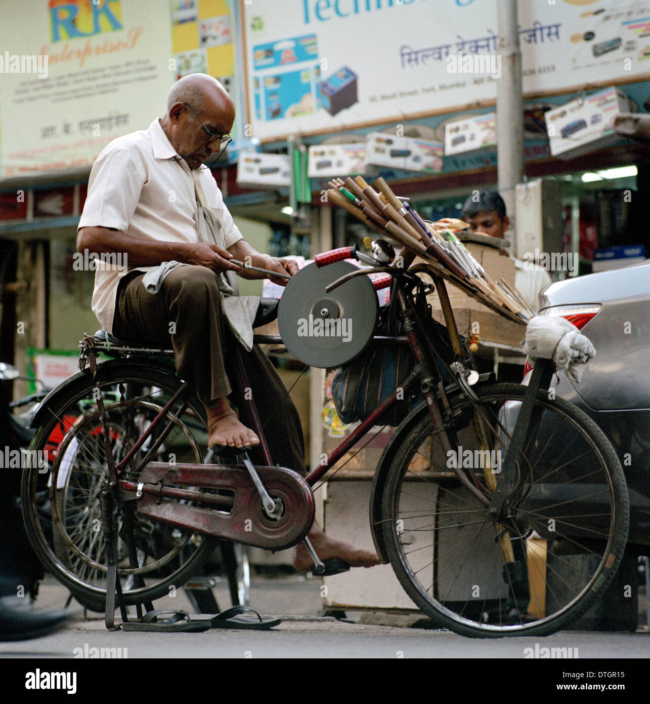 Street worker grinder in Mumbai in Maharashtra in India in South Asia. Work Labor Labour Manual Working Street Travel Wanderlust Stock Photo