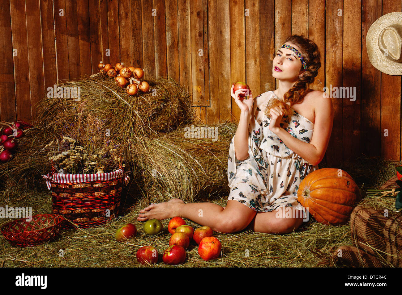 Attractive young girl sitting barefoot on the hay in the barn Stock Photo