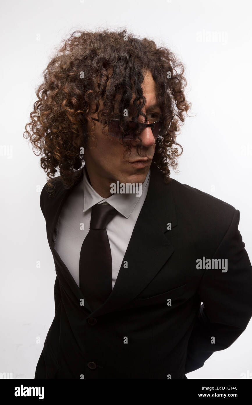Cropped portrait of mediterranean looking man with curly hair wearing  business suit and sun glasses Stock Photo - Alamy