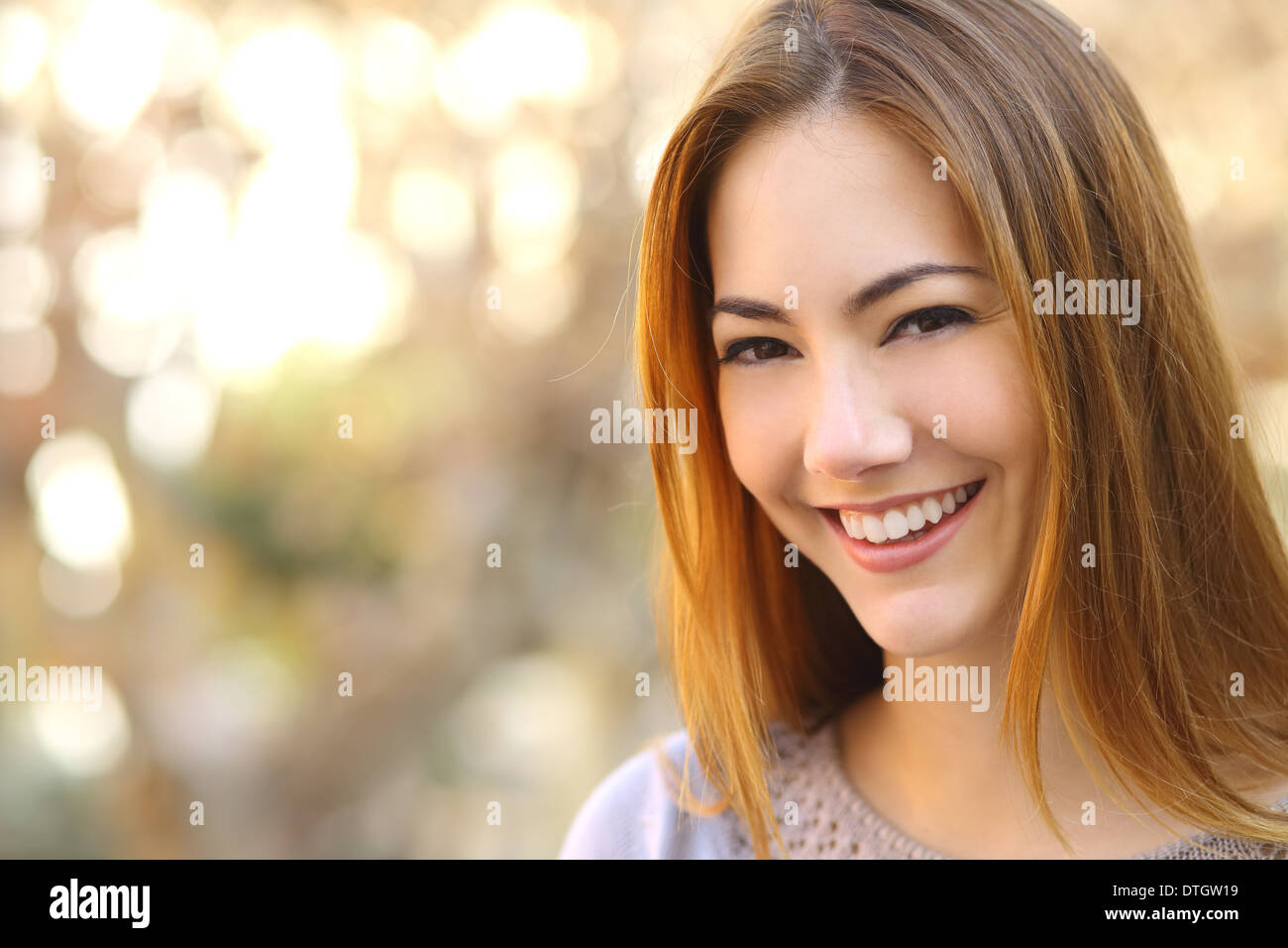 Portrait of a beautiful happy woman with a perfect white smile with a warmth background Stock Photo