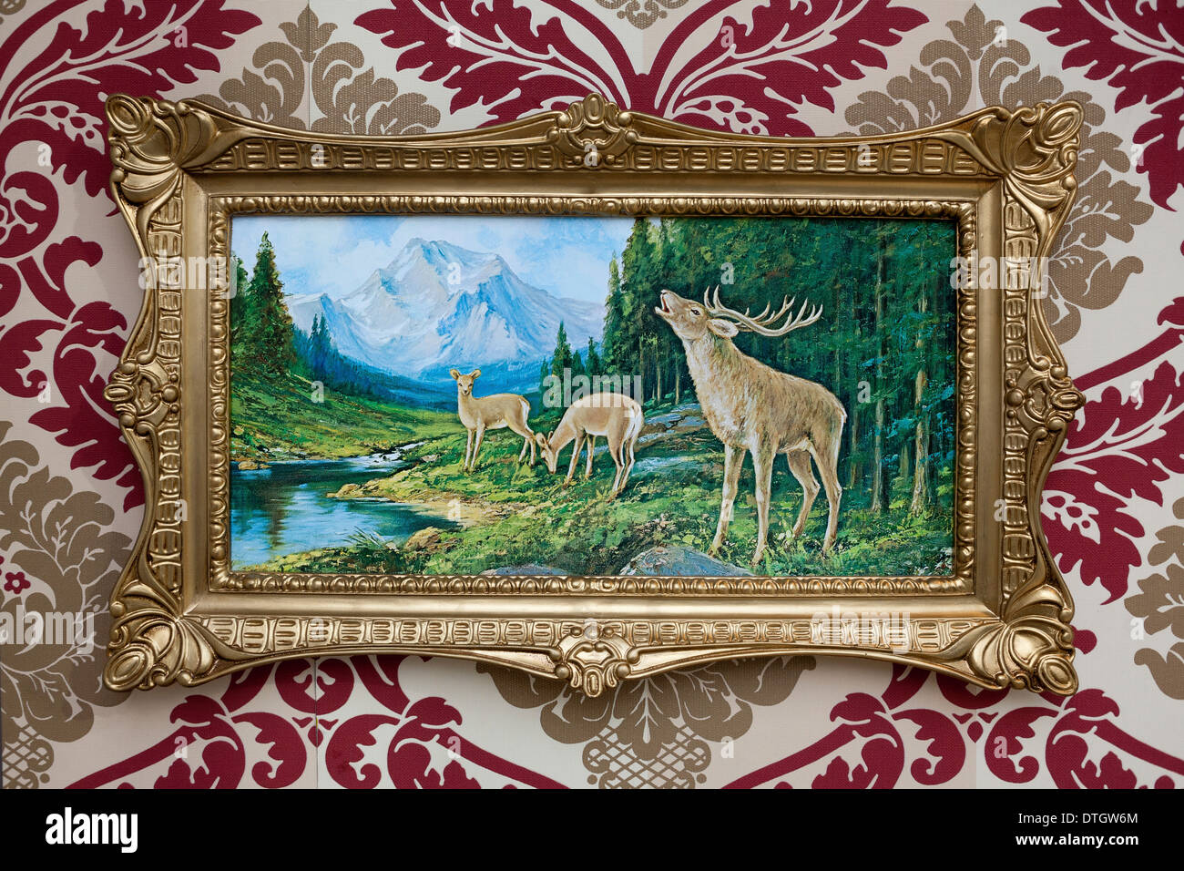 Trashy deer picture in a plastic gold frame on patterned wallpaper Stock Photo