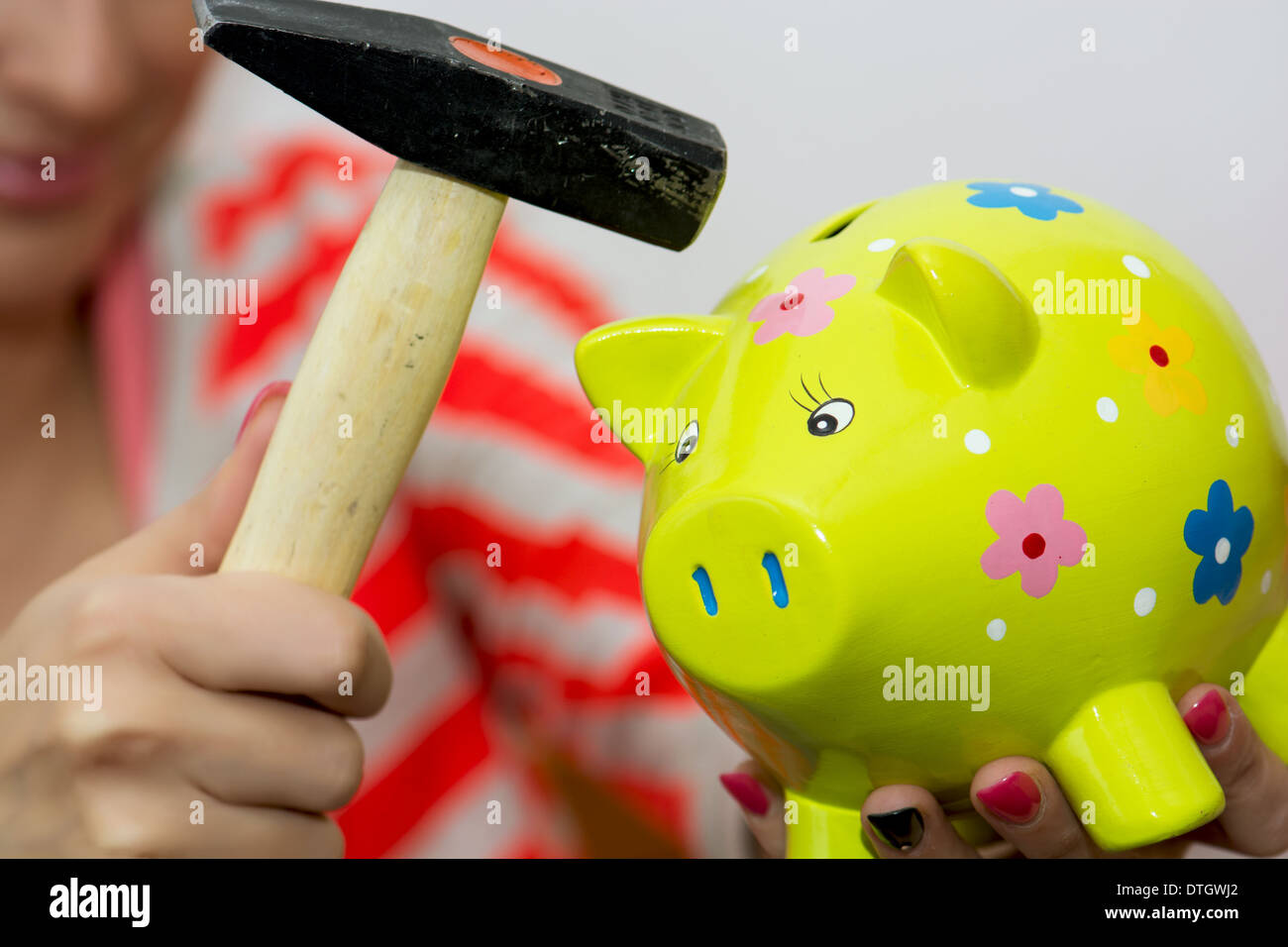 Young woman breaks a porcelain piggy bank with a hammer Stock Photo - Alamy