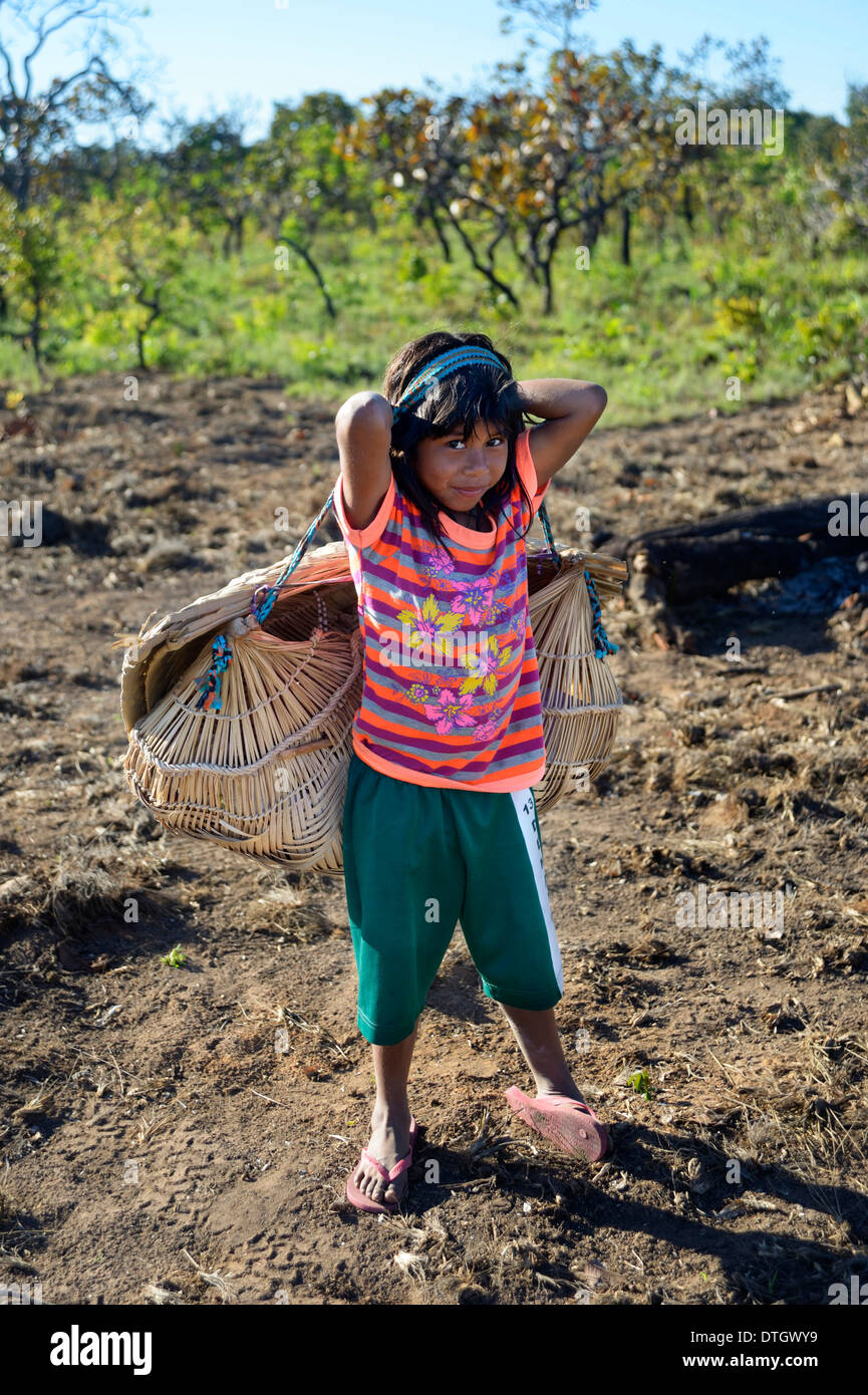 Girl carrying her little sister in a traditional basket on her back, village of the Xavantes people, Nova Vida near the mission Stock Photo