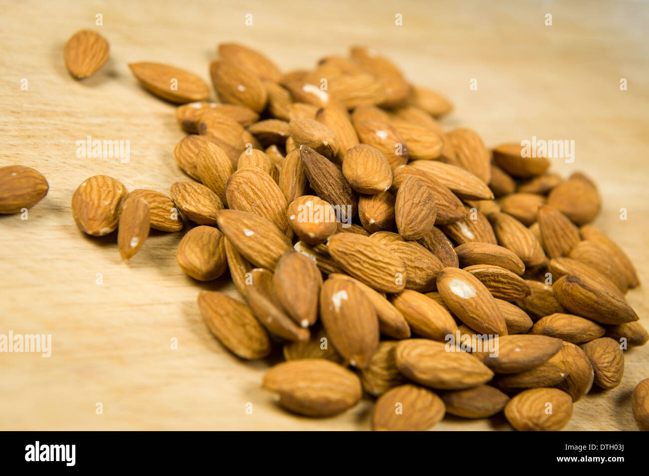 Close up photograph of shelled almonds on a wooden chopping board. Stock Photo