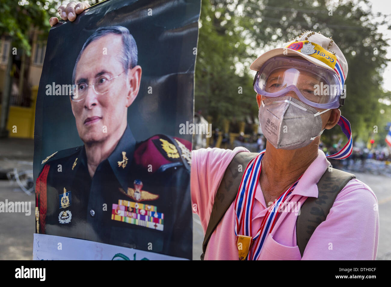 Bangkok, Thailand. 18th Feb, 2014. A Thai anti-government protestor holds up a portrait of Bhumibol Adulyadej, the King of Thailand, during a protest in Bangkok. Many of the anti-government protestors are monarchists who allege the elected government does not adequately support the monarchy. Anti-government protestors aligned with Suthep Thaugsuban and the People's Democratic Reform Committee (PDRC) clashed with police Tuesday. Protestors opened fire on police with at rifles and handguns. Police returned fire with live ammunition and rubber bullets. Credit:  ZUMA Press, Inc./Alamy Live News Stock Photo