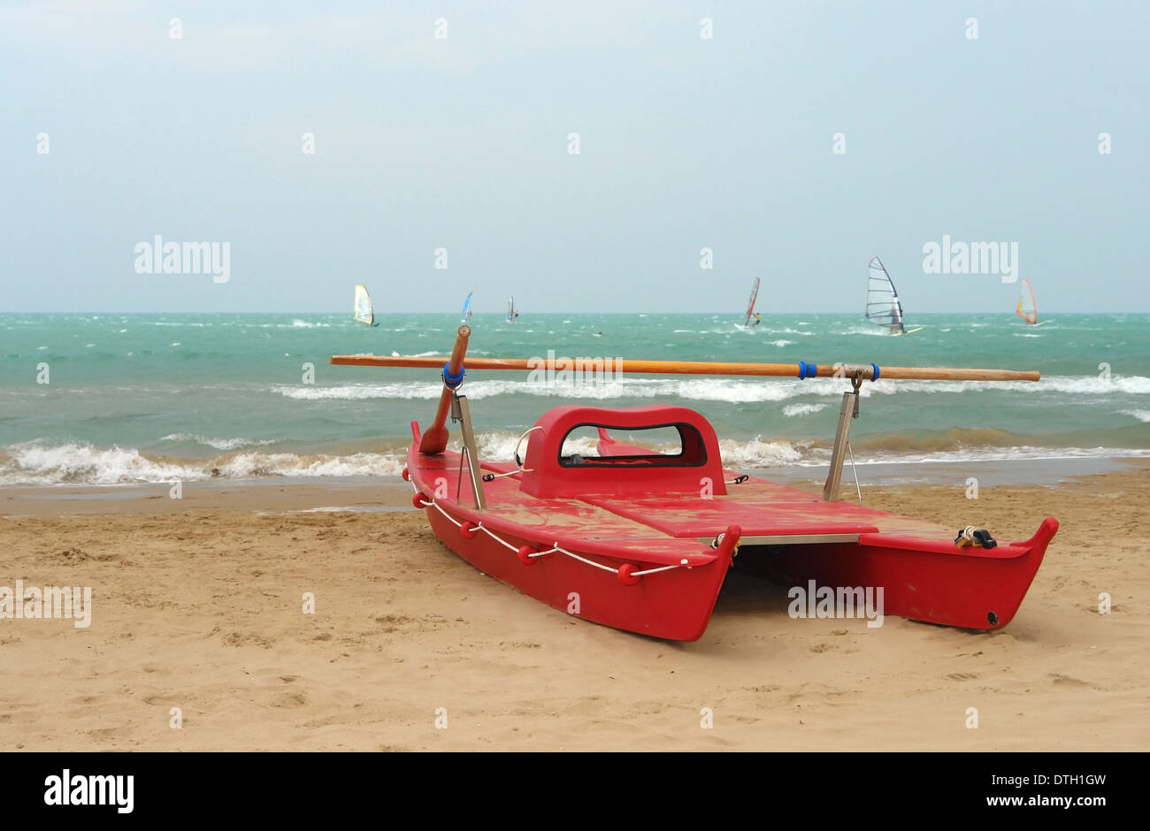 holiday scenery showing a red boat and surfers at a beach in Southern Italy Stock Photo