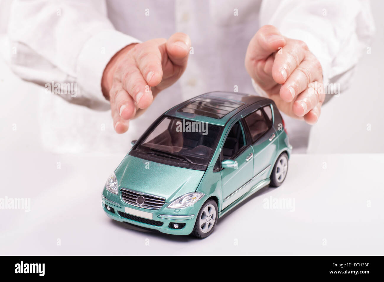 Hands lay protectively around a car. Stock Photo
