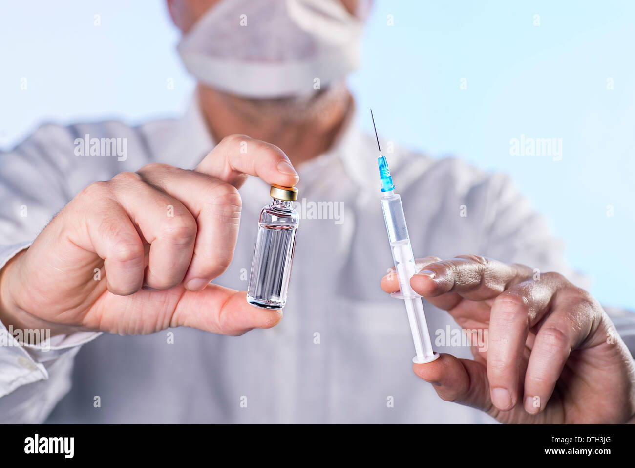 Doctor holding a syringe and a vial of vaccine in their hands. Stock Photo