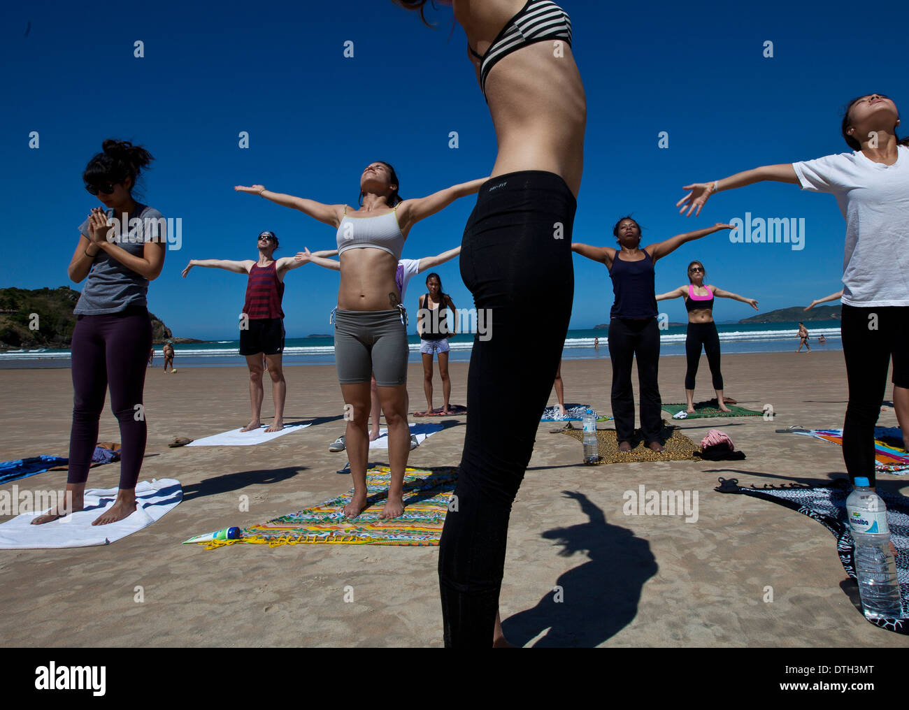 Young people practicing yoga at Geriba beach, Armacao de Buzios, Rio de Janeiro State, Brazil. Beautiful thin woman lean belly Stock Photo