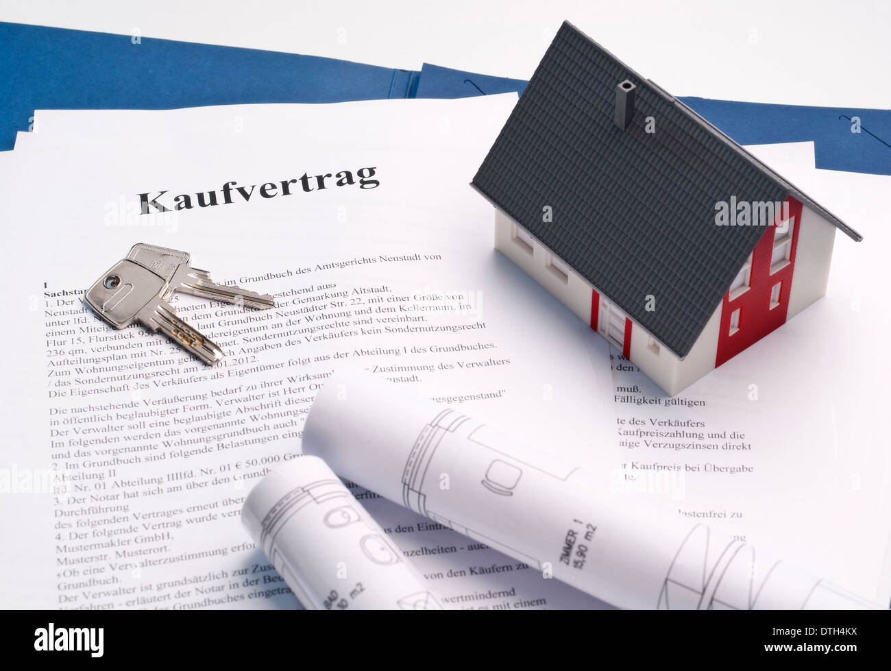 Model house, house keys and blueprints on a purchase contract for a property. Stock Photo