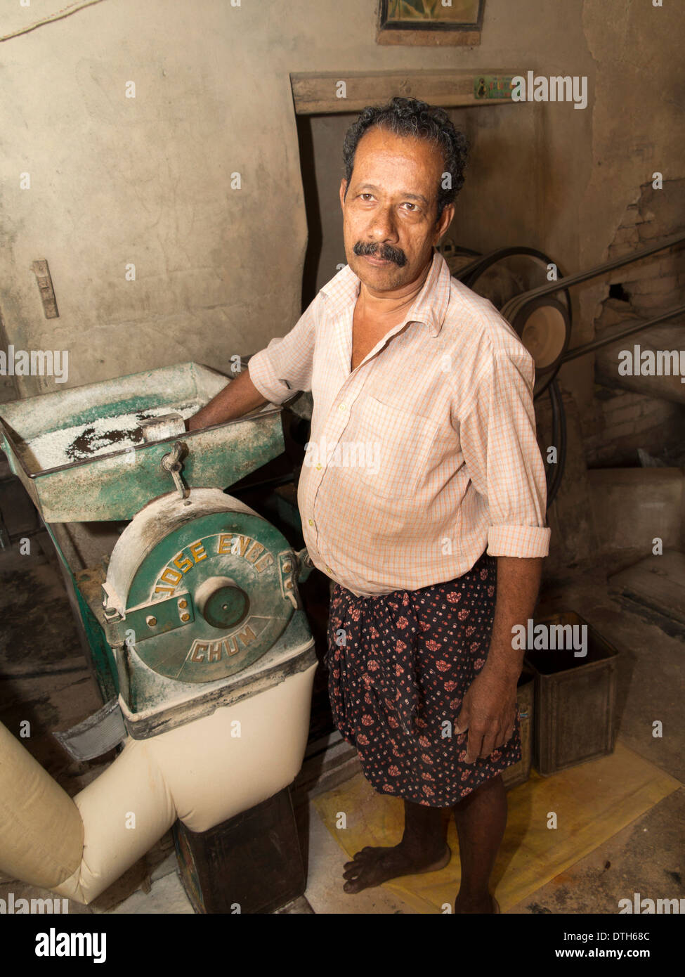 India, Kerala, backwaters, man milling rice flour in small riverside mill Stock Photo