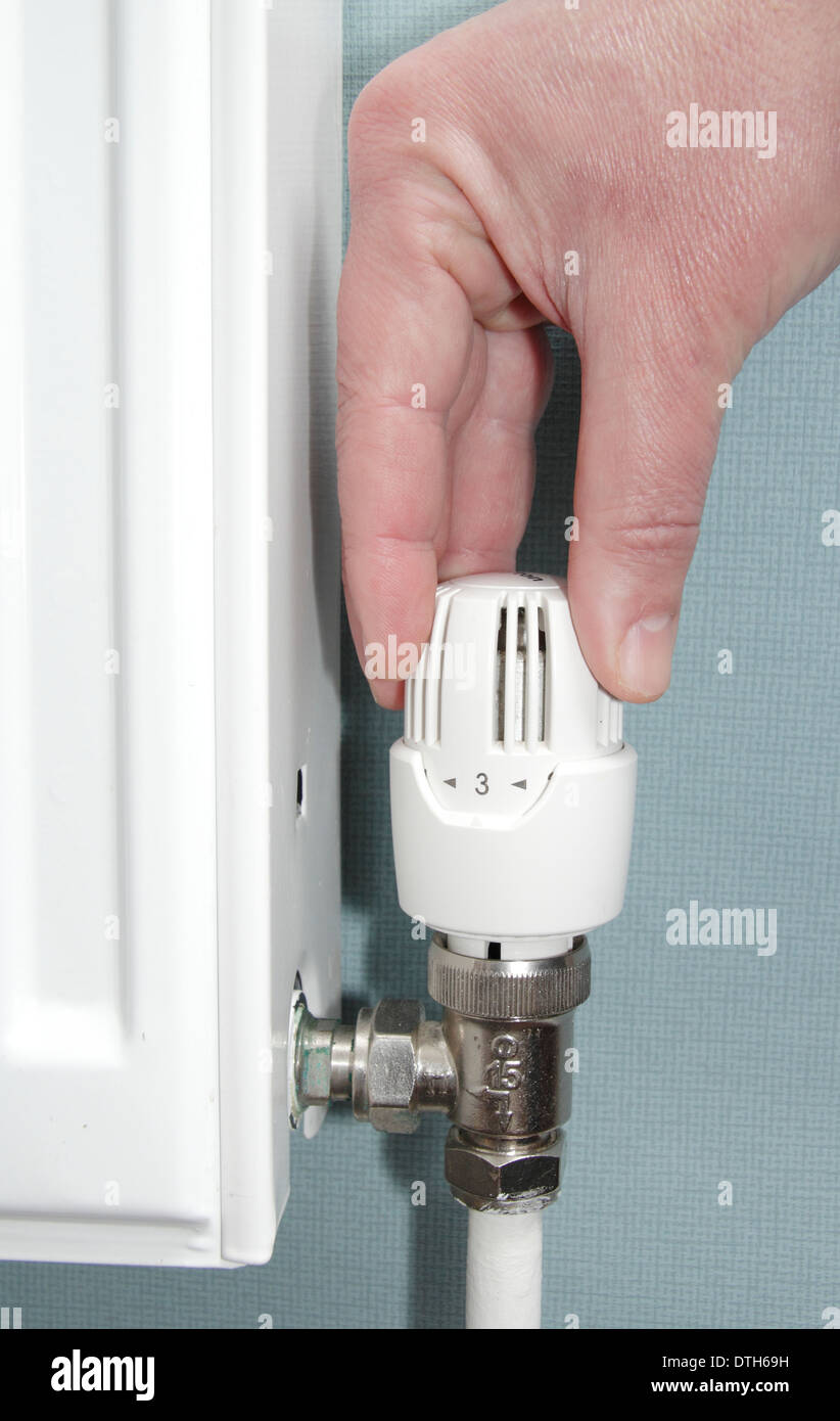 Man turning radiator valve/heating control up down in lounge of domestic home, England, UK (model released) Stock Photo