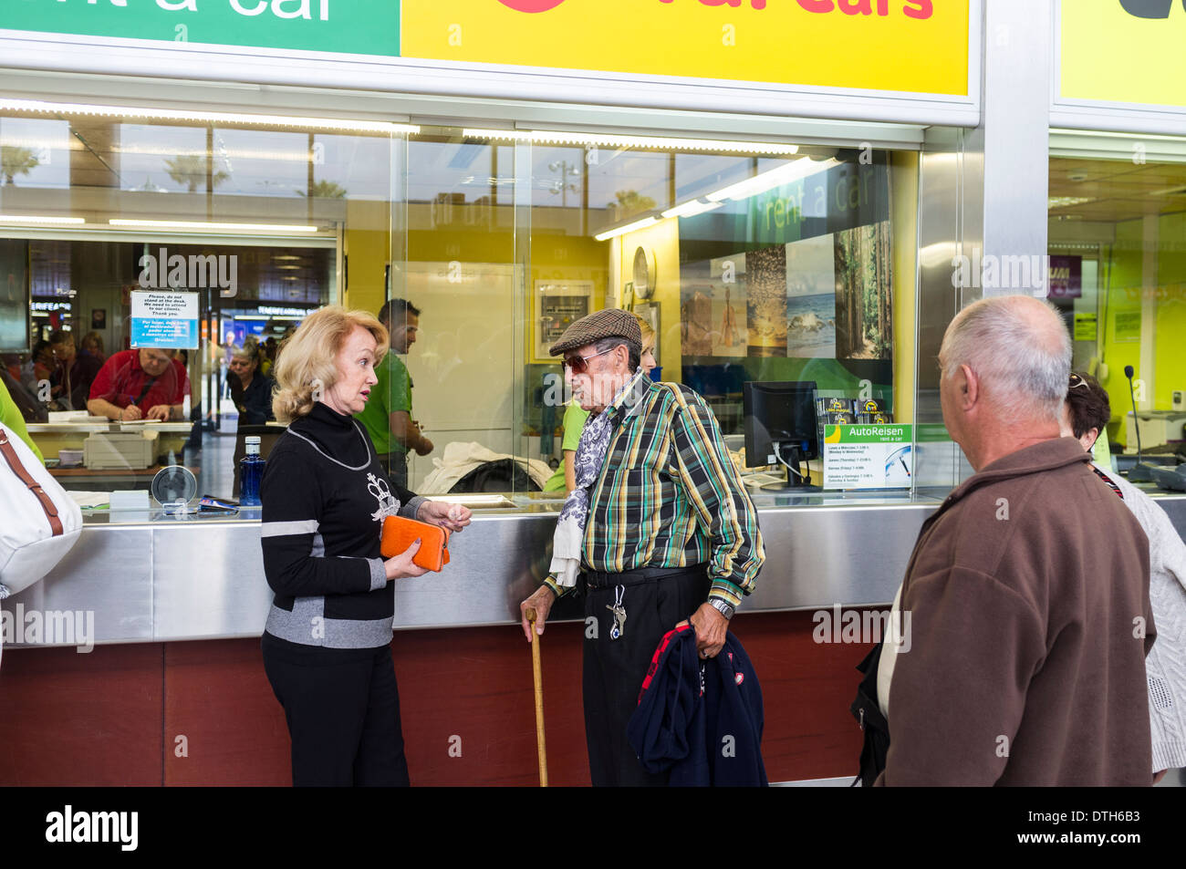 A couple at a car hire desk in the arrivals area at Tenerife Sur airport, Canary Islands, Spain. Stock Photo