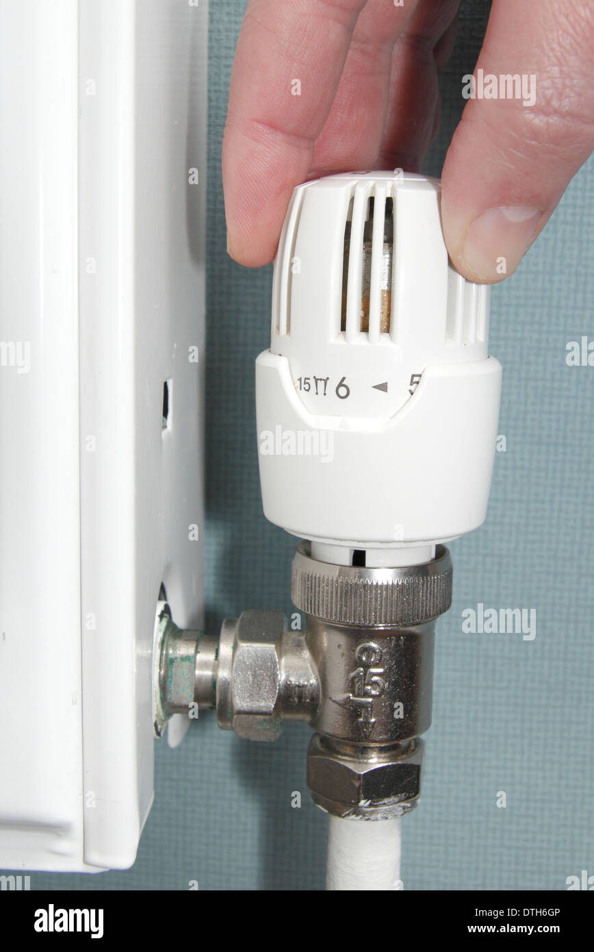Man turning radiator valve/heating control up down in lounge of domestic home, England, UK (model released) Stock Photo