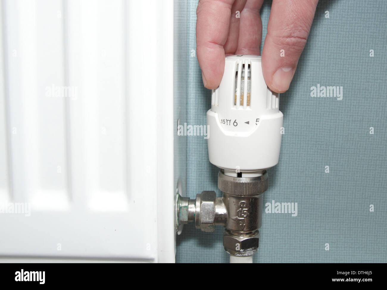 Man turning radiator/thermostatic valve/heating control up down in lounge of domestic home, England, UK (model released) Stock Photo