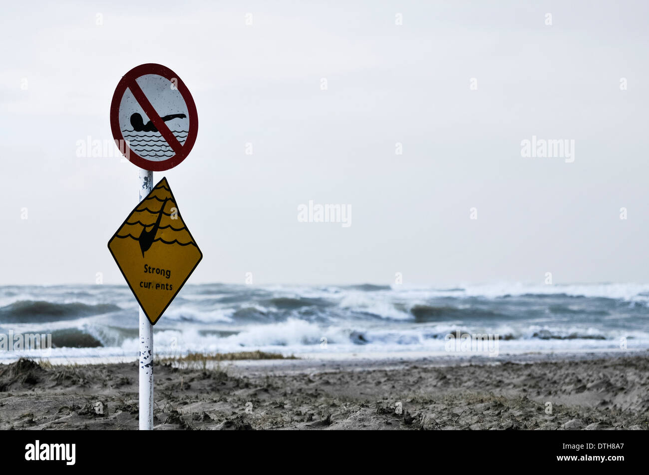 Sign warning of strong currents, and prohibiting swimming against a stormy sea Stock Photo