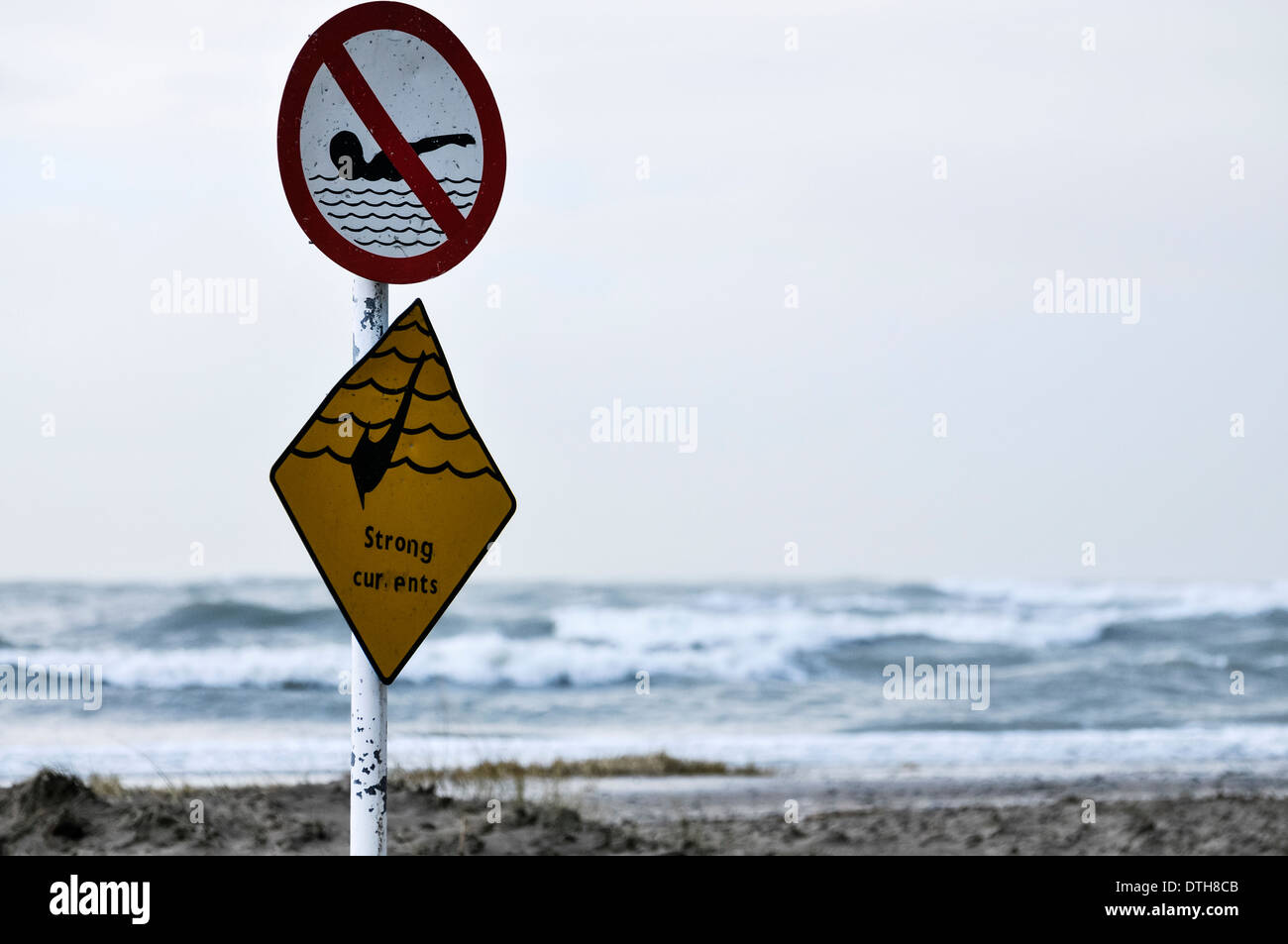 Sign warning of strong currents, and prohibiting swimming against a stormy sea Stock Photo