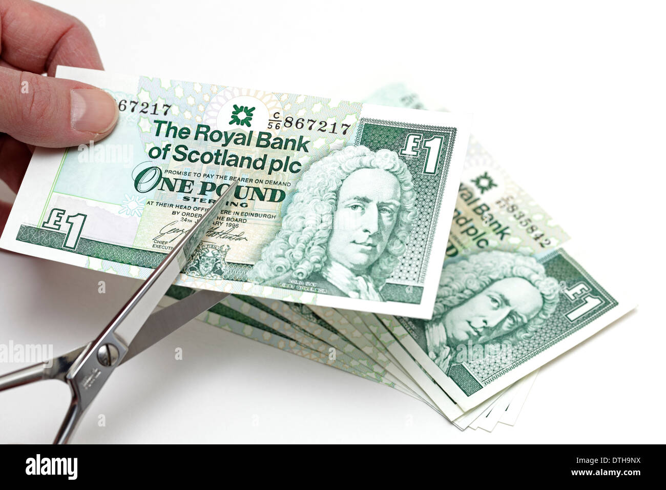 Cutting a Scottish One Pound note with a pair of scissors, Scotland, UK Stock Photo